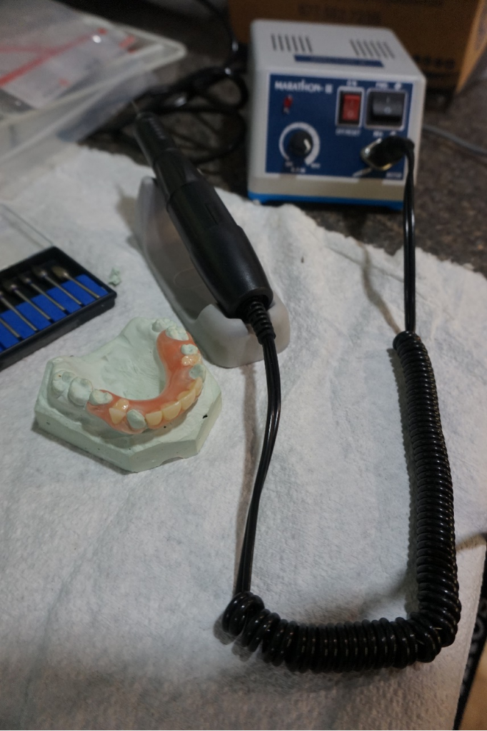 A mold of a client’s mouth is placed next to other dental tools.