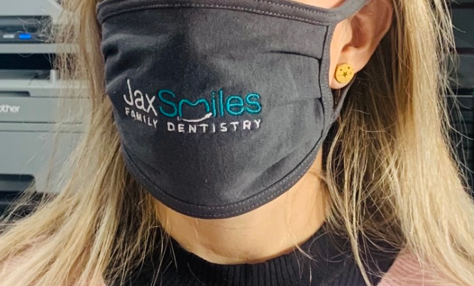 A woman wearing a Jax Smiles Dentistry mask.