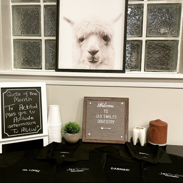 A quote of the month slate, baby goat picture, welcome note, and aprons on a table at Jax Smiles Dentistry