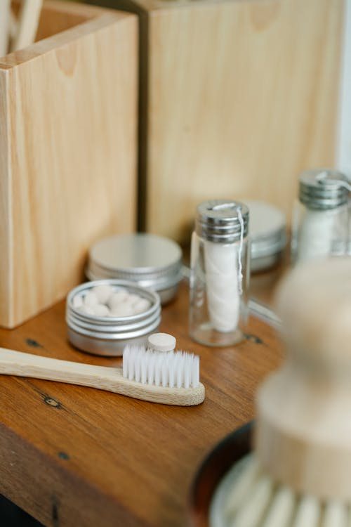 An image of dental floss in a container near a toothbrush on a wooden table