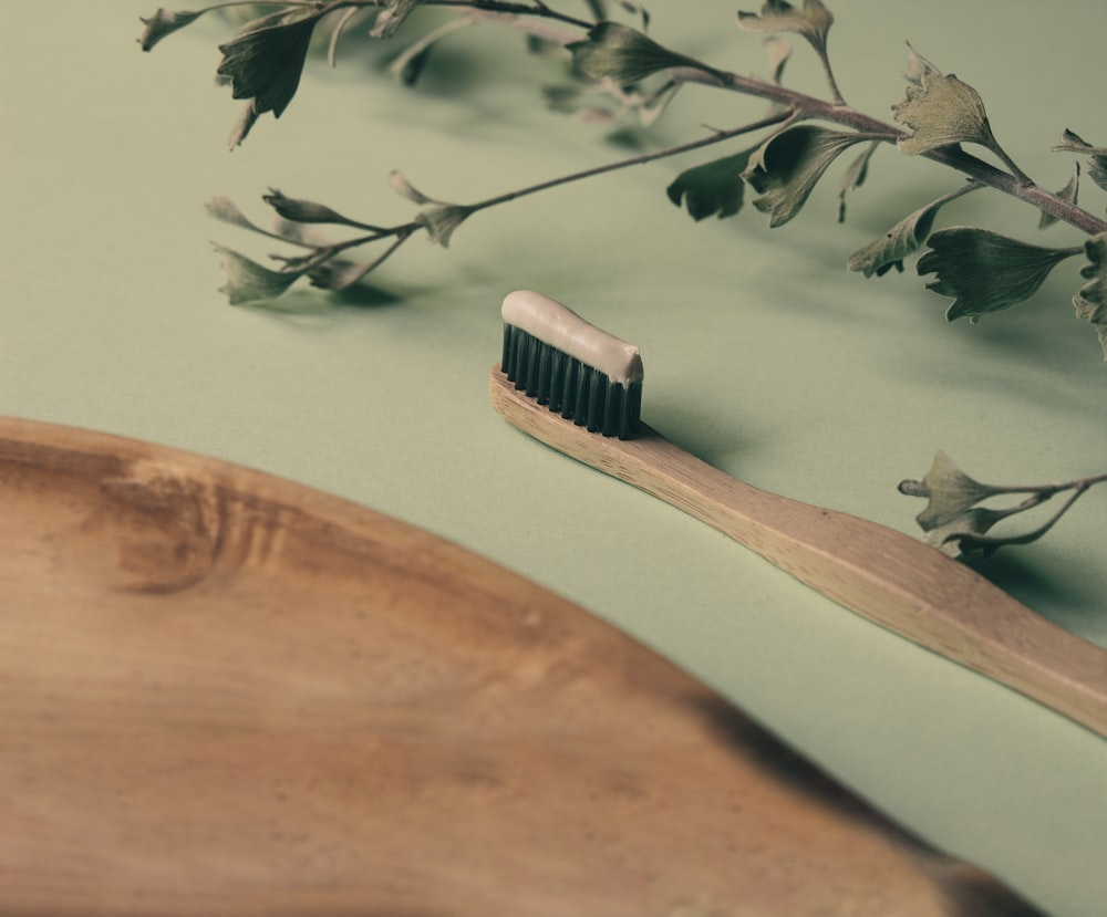 An image of a brown wooden toothbrush on a green surface
