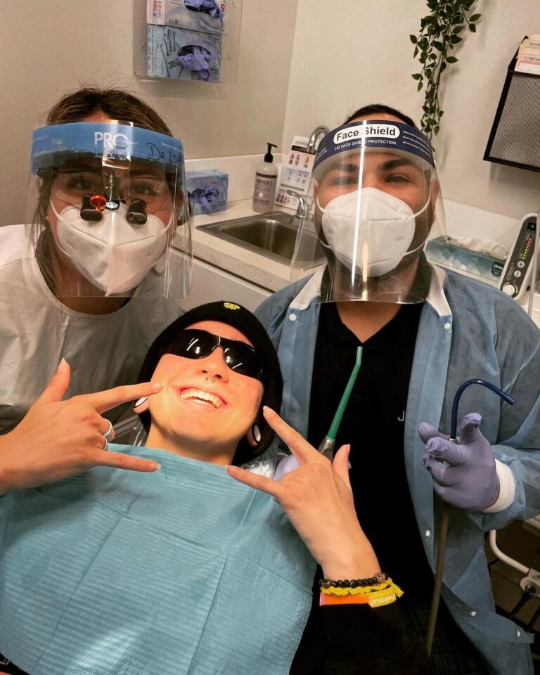 An image of a satisfied patient posing confidently with two dentists